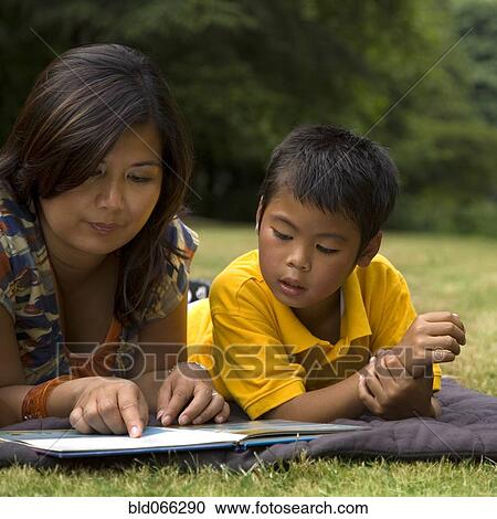 Stock Image - Asian mother reading book to son. Fotosearch