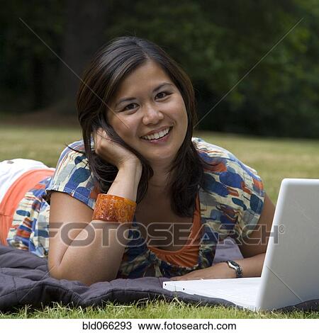 Asian woman laying in park with laptop View Large Photo Image Stock Image - Asian woman laying in park with laptop. Fotosearch