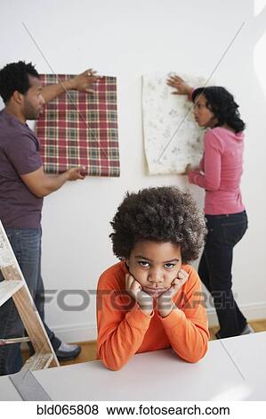 Stock Photo - Bored African boy waiting while parents choose wallpaper. Fotosearch