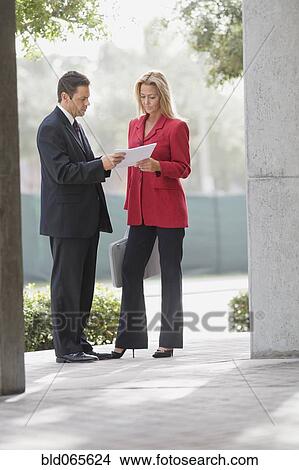 Businesspeople reviewing paperwork outdoors View Large Photo Image Picture - Businesspeople reviewing paperwork outdoors. Fotosearch