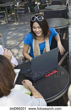 Stock Image - Chinese businesspeople working at cafe. Fotosearch