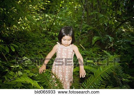 Stock Image - Chinese girl walking through forest. Fotosearch