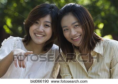 Stock Image - Chinese woman pointing with friend. Fotosearch