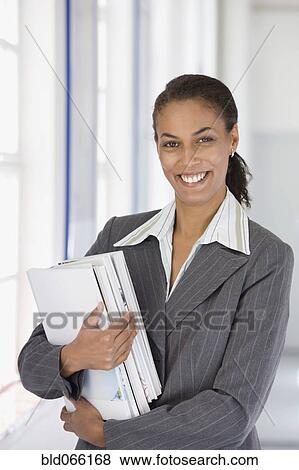 Confident African businesswoman holding paperwork View Large Photo Image Stock Photo - Confident African businesswoman holding paperwork. Fotosearch