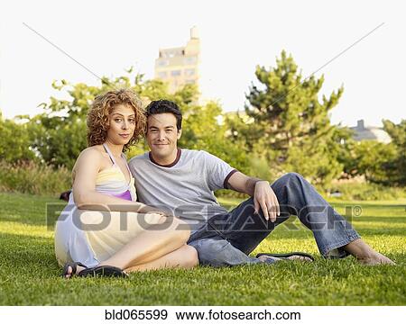 Couple sitting in grass in city park View Large Photo Image Stock Photo - Couple sitting in grass in city park. Fotosearch