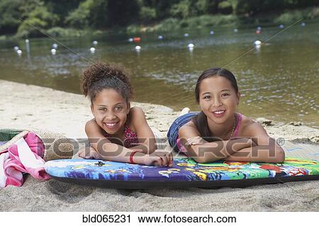 Friends laying on boogie board near lake View Large Photo Image Stock Image - Friends laying on boogie board near lake. Fotosearch