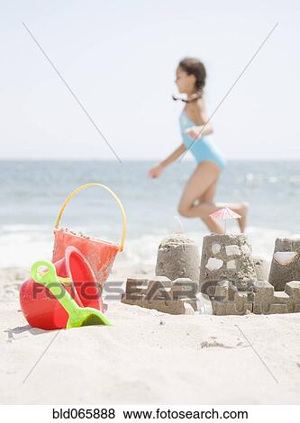 Stock Photo - Hispanic girl and sand castle on beach. Fotosearch