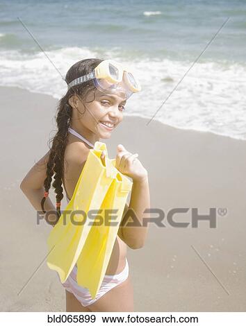 Stock Photo - Hispanic girl carrying flippers and goggles. Fotosearch