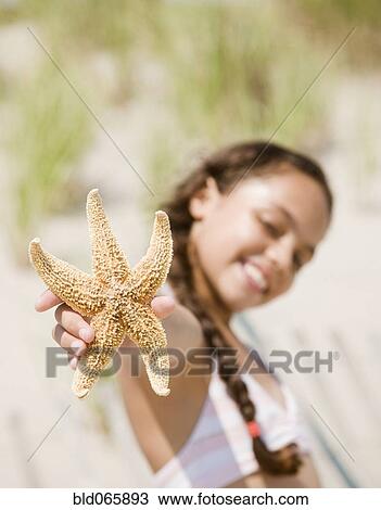 Stock Image - Hispanic girl holding starfish. Fotosearch