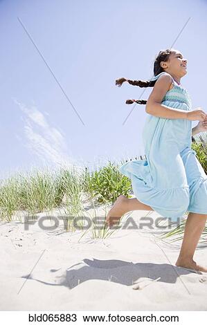 Stock Image - Hispanic girl running at beach. Fotosearch