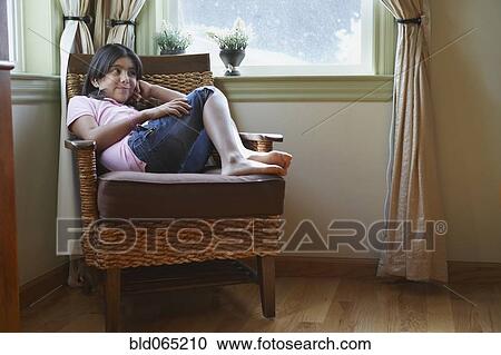 Stock Image - Hispanic girl sitting in armchair. Fotosearch