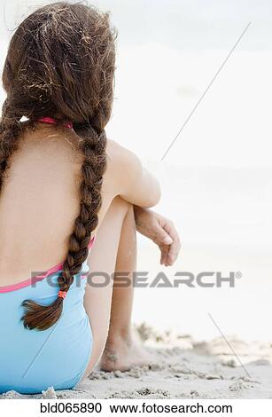 Stock Image - Hispanic girl sitting on beach. Fotosearch