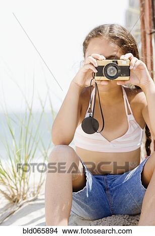 Picture - Hispanic girl taking photograph on beach. Fotosearch