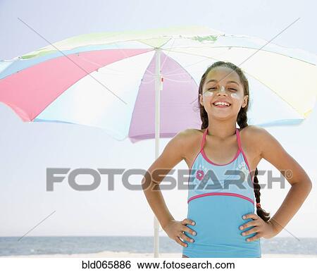 Hispanic girl with sunscreen under umbrella on beach View Large Photo Image Stock Photograph - Hispanic girl with sunscreen under umbrella on beach. Fotosearch