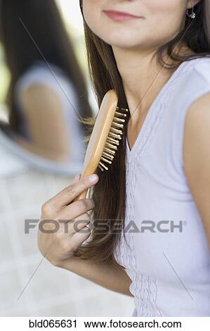 Stock Image - Hispanic woman brushing her hair. Fotosearch