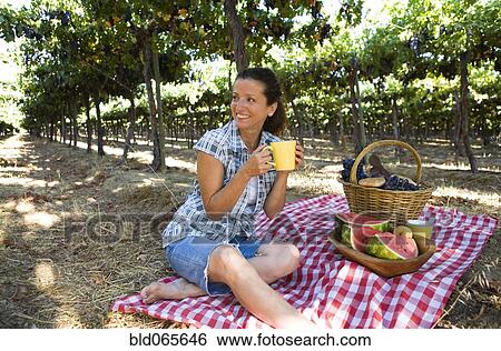 Stock Photograph - Hispanic woman having picnic in vineyard. Fotosearch
