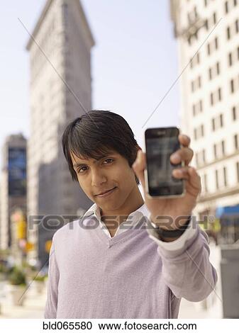 Indian man holding out cell phone View Large Photo Image Stock Image - Indian man holding out cell phone. Fotosearch