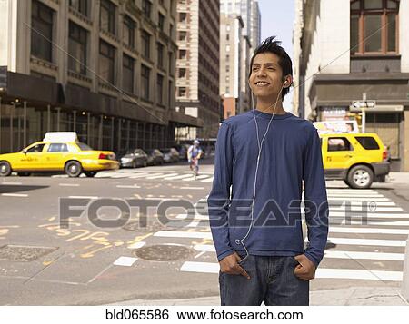 Stock Photograph - Indian man on city street listening to mp3 player. Fotosearch