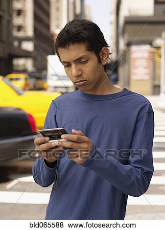 Stock Photo - Indian man on city street text messaging. Fotosearch