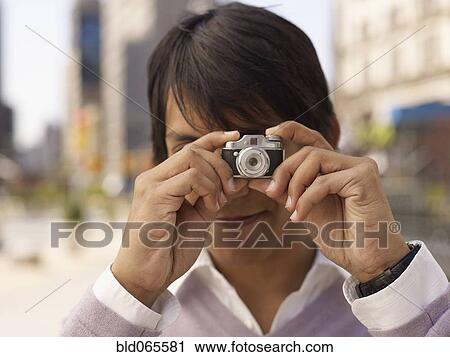 Indian man taking photograph with miniature camera View Large Photo Image Stock Image - Indian man taking photograph with miniature camera. Fotosearch