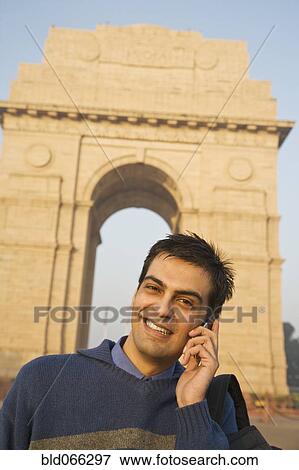 Stock Photo - Indian man talking on cell phone near the India Gate. Fotosearch