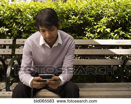 Indian man text messaging in park View Large Photo Image Stock Image - Indian man text messaging in park. Fotosearch