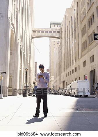 Indian man text messaging on city sidewalk View Large Photo Image Picture - Indian man text messaging on city sidewalk. Fotosearch