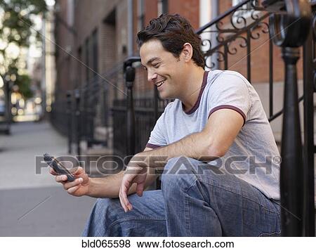 Man on front stoop text messaging on cell phone View Large Photo Image Stock Photo - Man on front stoop text messaging on cell phone. Fotosearch