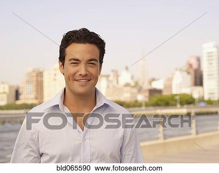 Man standing at waterfront with cityscape in background View Large Photo Image Stock Image - Man standing at waterfront with cityscape in background. Fotosearch