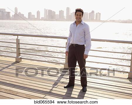 Man standing on boardwalk on waterfront View Large Photo Image Picture - Man standing on boardwalk on waterfront. Fotosearch