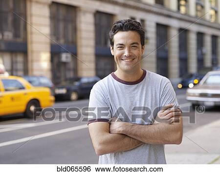 Stock Photograph - Man with arms crossed on city street. Fotosearch