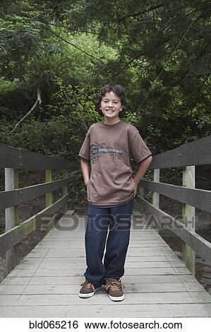 Stock Photograph - Mixed race boy crossing wooden bridge. Fotosearch