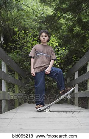Stock Photo - Mixed race boy standing with skateboard. Fotosearch
