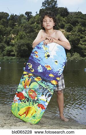 Mixed race boy with boogie board near lake View Large Photo Image Stock Photo - Mixed race boy with boogie board near lake. Fotosearch