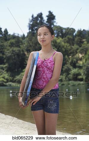 Mixed race girl holding boogie board near lake View Large Photo Image Stock Photo - Mixed race girl holding boogie board near lake. Fotosearch