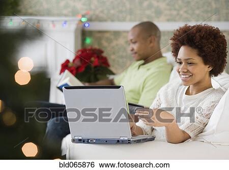 Mixed race woman buying Christmas presents online with credit card View Large Photo Image Stock Photograph - Mixed race woman buying Christmas presents online with credit card. Fotosearch