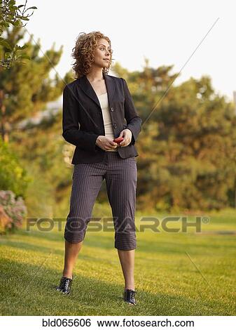 Stock Photograph - Mixed race woman holding cell phone in park. Fotosearch