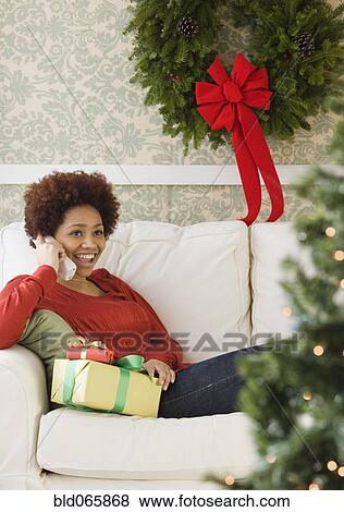 Stock Photo - Mixed race woman holding Christmas presents talking on telephone. Fotosearch
