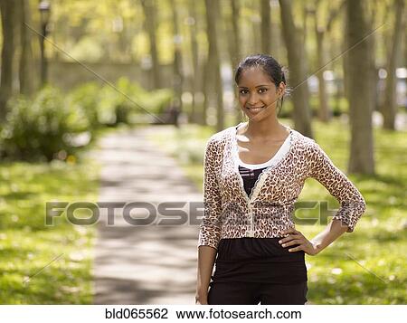 Mixed race woman standing with hands on hips in park View Large Photo Image Stock Image - Mixed race woman standing with hands on hips in park. Fotosearch