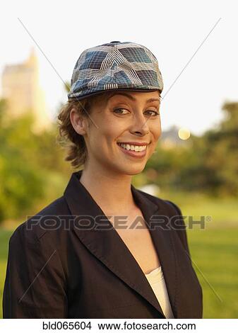 Picture - Mixed race woman wearing cap in park. Fotosearch