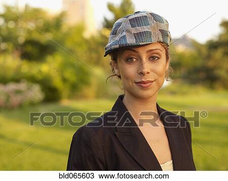 Stock Image - Mixed race woman wearing cap in park. Fotosearch