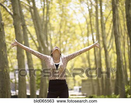Mixed race woman with arms outstretched in park View Large Photo Image Stock Image - Mixed race woman with arms outstretched in park. Fotosearch