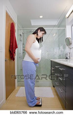 Pregnant Asian woman standing on scales View Large Photo Image Stock Photograph - Pregnant Asian woman standing on scales. Fotosearch