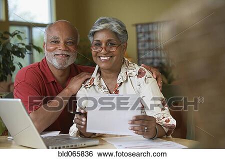 Stock Photograph - Senior African couple paying bills online. Fotosearch