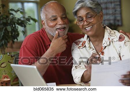 Stock Photography - Senior African couple paying bills online. Fotosearch