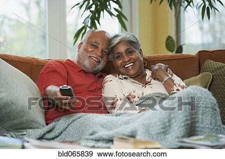 Stock Photo - Senior African couple watching television. Fotosearch