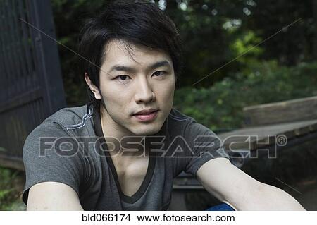 Picture - Serious Japanese man sitting outdoors. Fotosearch