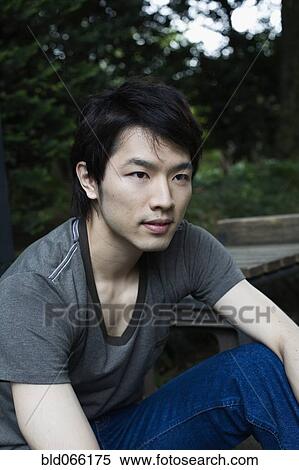 Stock Photography - Serious Japanese man sitting outdoors. Fotosearch