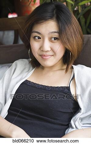 Skeptical Chinese woman sitting in chair View Large Photo Image Stock Image - Skeptical Chinese woman sitting in chair. Fotosearch