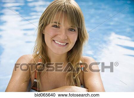 Stock Image - Smiling Hispanic woman near swimming pool. Fotosearch